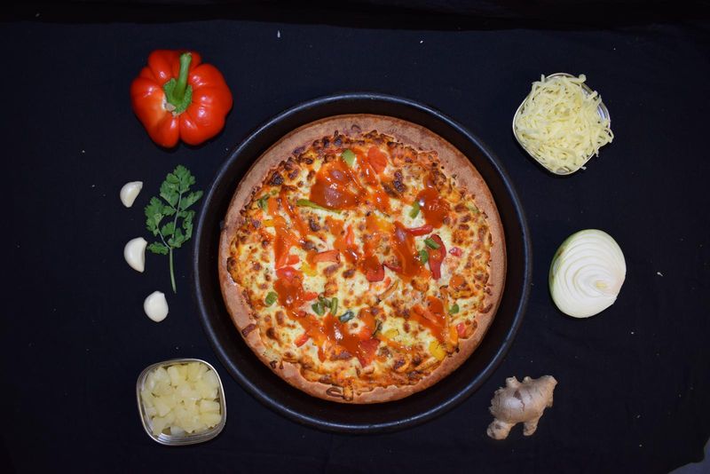 Pizza with a red chilli drizzle, capsicum and pineapple